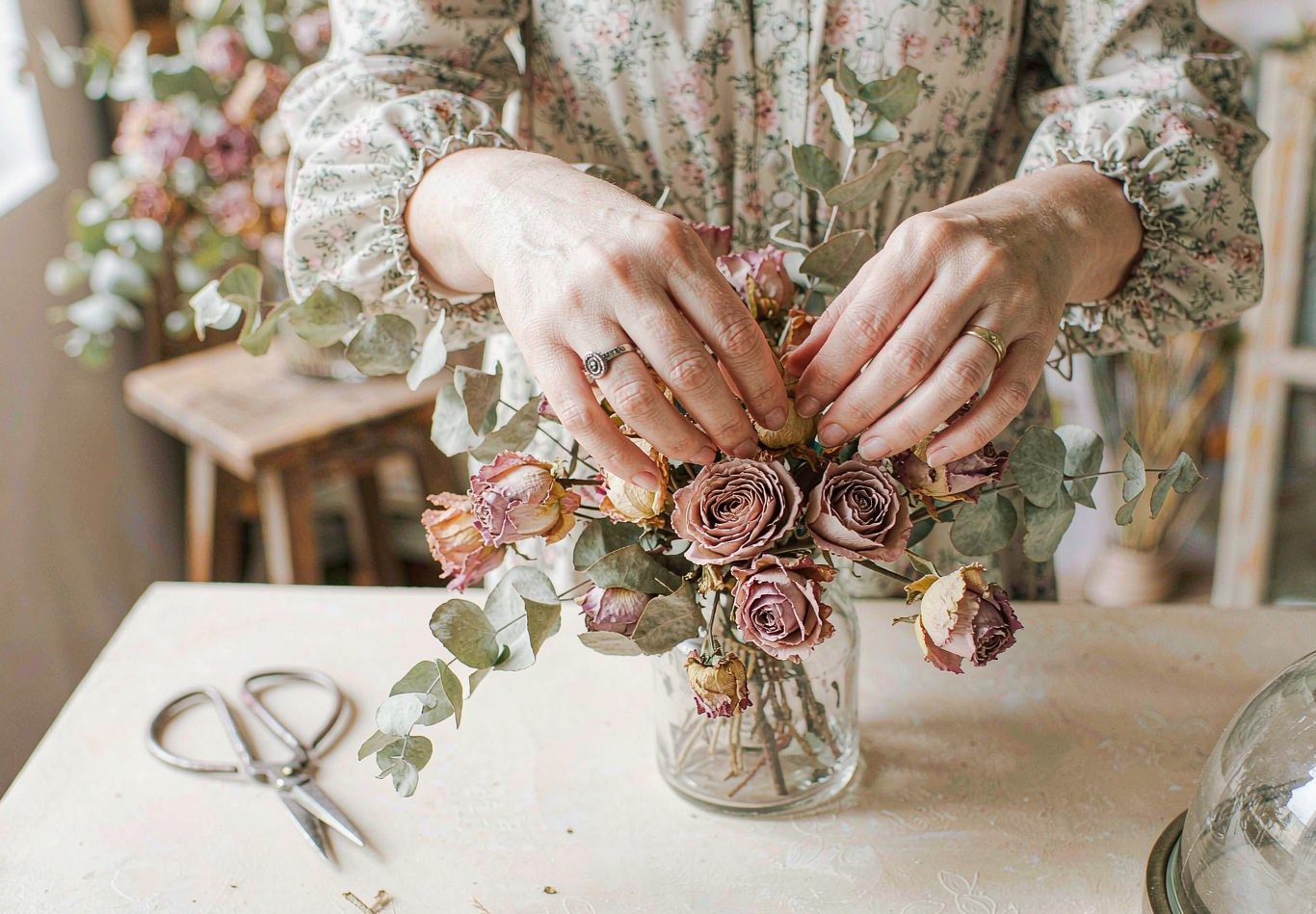 Florist hands arranging preserved blush roses in a bright studio.