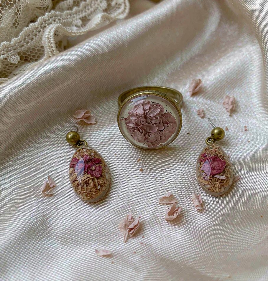 Handmade resin ring and earrings with dried blush flower petals, on ivory silk.